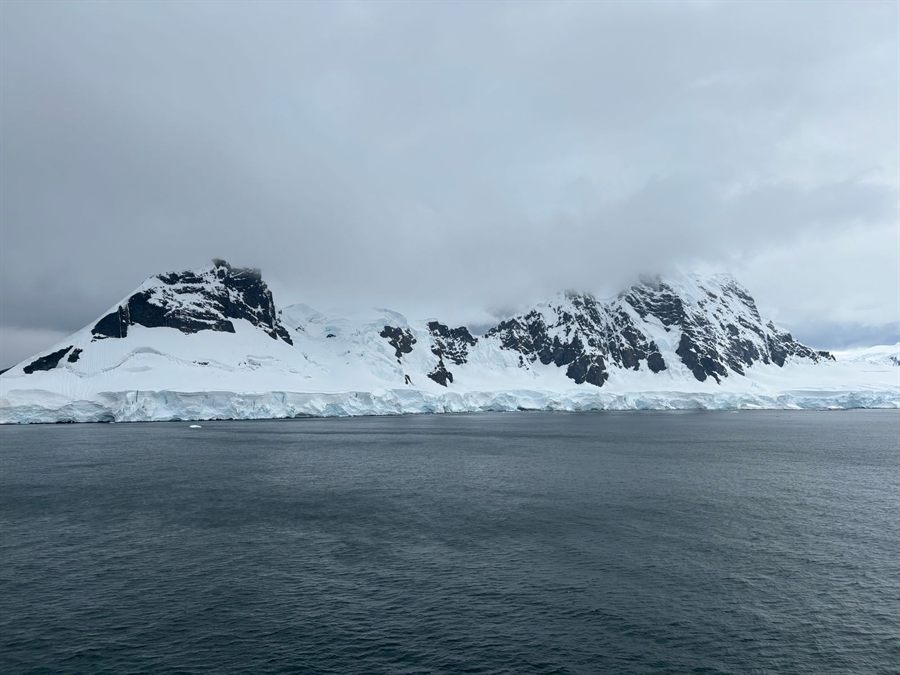 Glacier-covered Antarctic coastline under low grey cloud seen from the sea